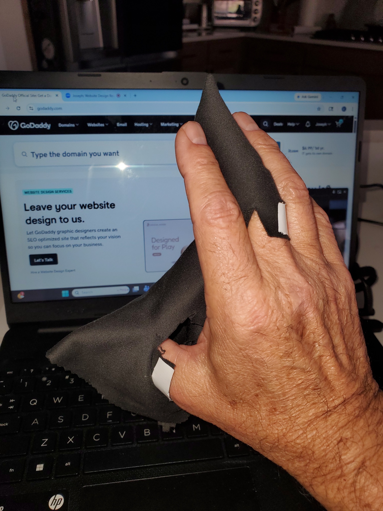 Hand cleaning laptop screen with cloth.