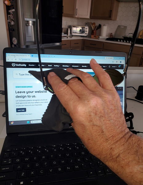 Cleaning glasses in front of laptop screen.