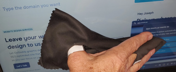 Hand cleaning computer screen with cloth.